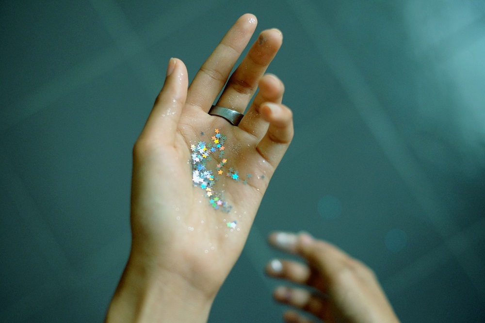A hand full of glitter sequins shining. Image taken by Mink Mingle, a talented Thai photographer.